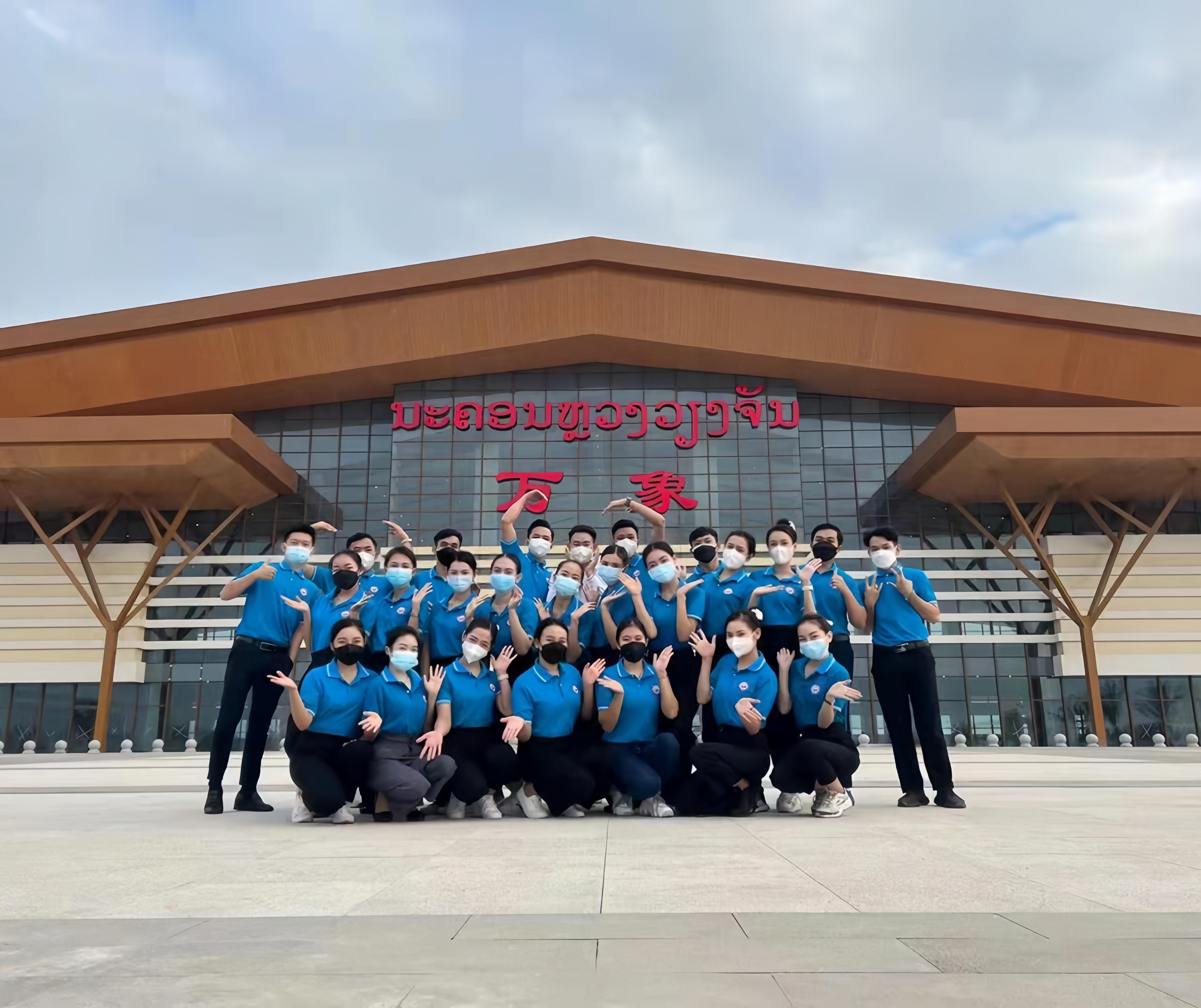 學(xué)生上崗前在老撾萬(wàn)象高鐵站前合影（其中5人為貴陽(yáng)職業(yè)技術(shù)學(xué)院培訓(xùn)班學(xué)生）。 貴陽(yáng)職業(yè)技術(shù)學(xué)院供圖