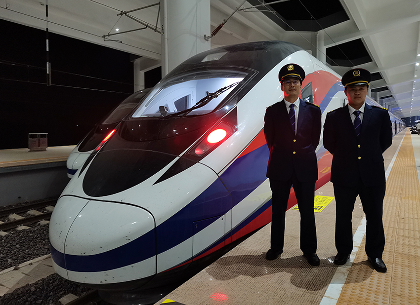 劉銀能（右一）與中國師父鄔俊鴻在動車組前合影。受訪者供圖